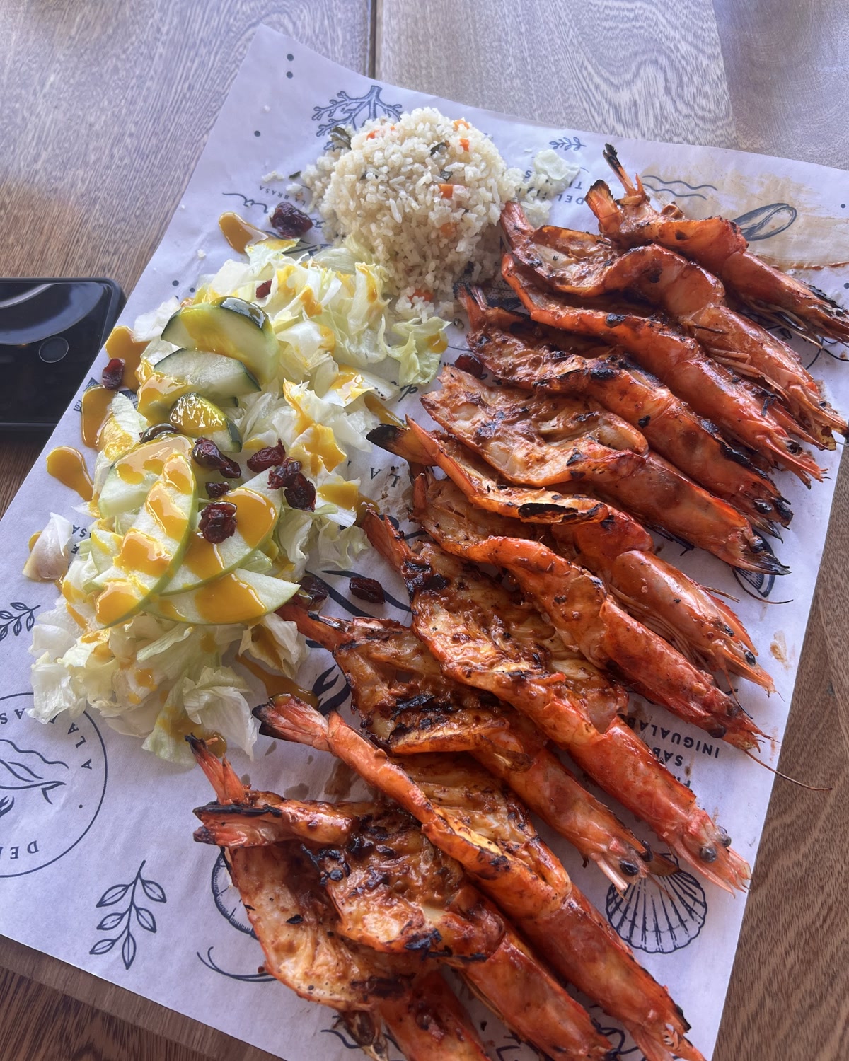 Camarones a la talla alineados sobre el papel de marca de Marena, con ensalada y arroz.