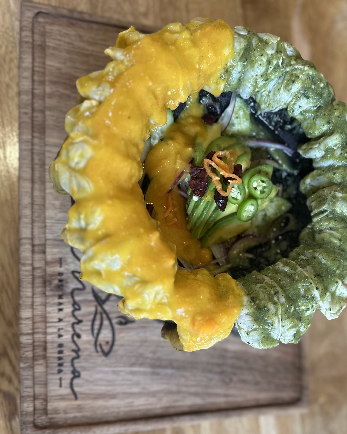 Aguachile servido en molcajete de piedra, con la salsa amarilla y la verde enfrentadas.